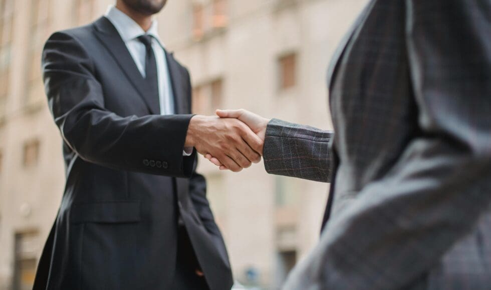 Two professionals shaking hands in a business setting.